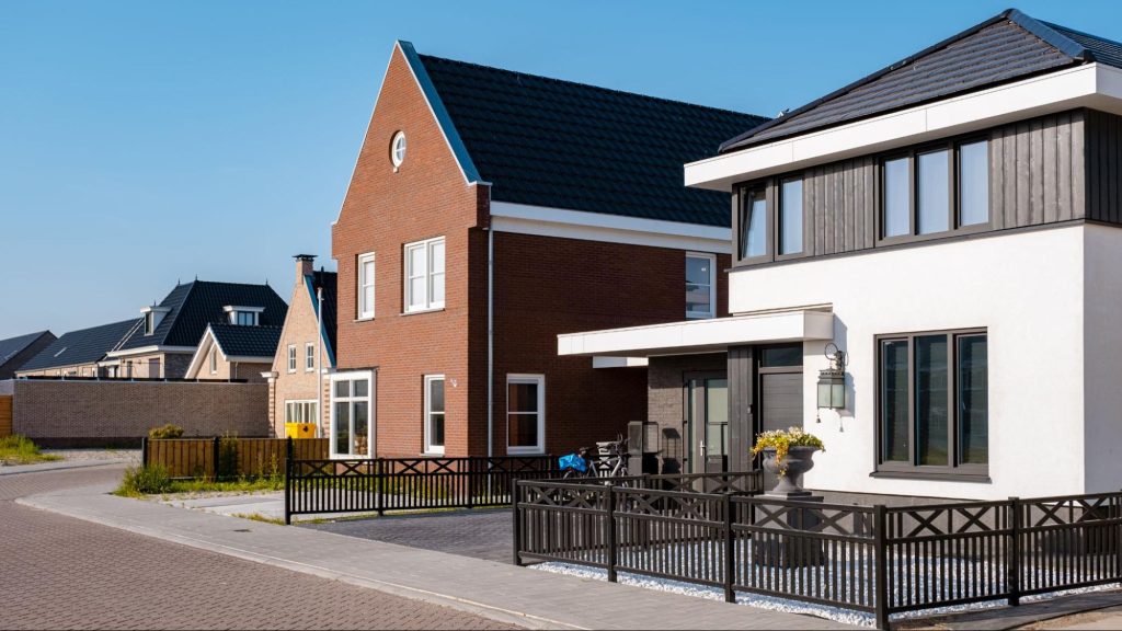 A suburban neighborhood featuring modern Dutch-style family homes, each bordered by clean-lined steel fences.