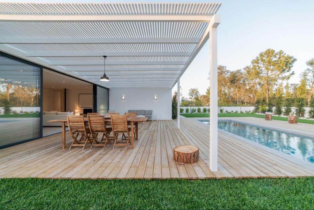 Modern villa with pool and wood deck featuring a covered patio area.