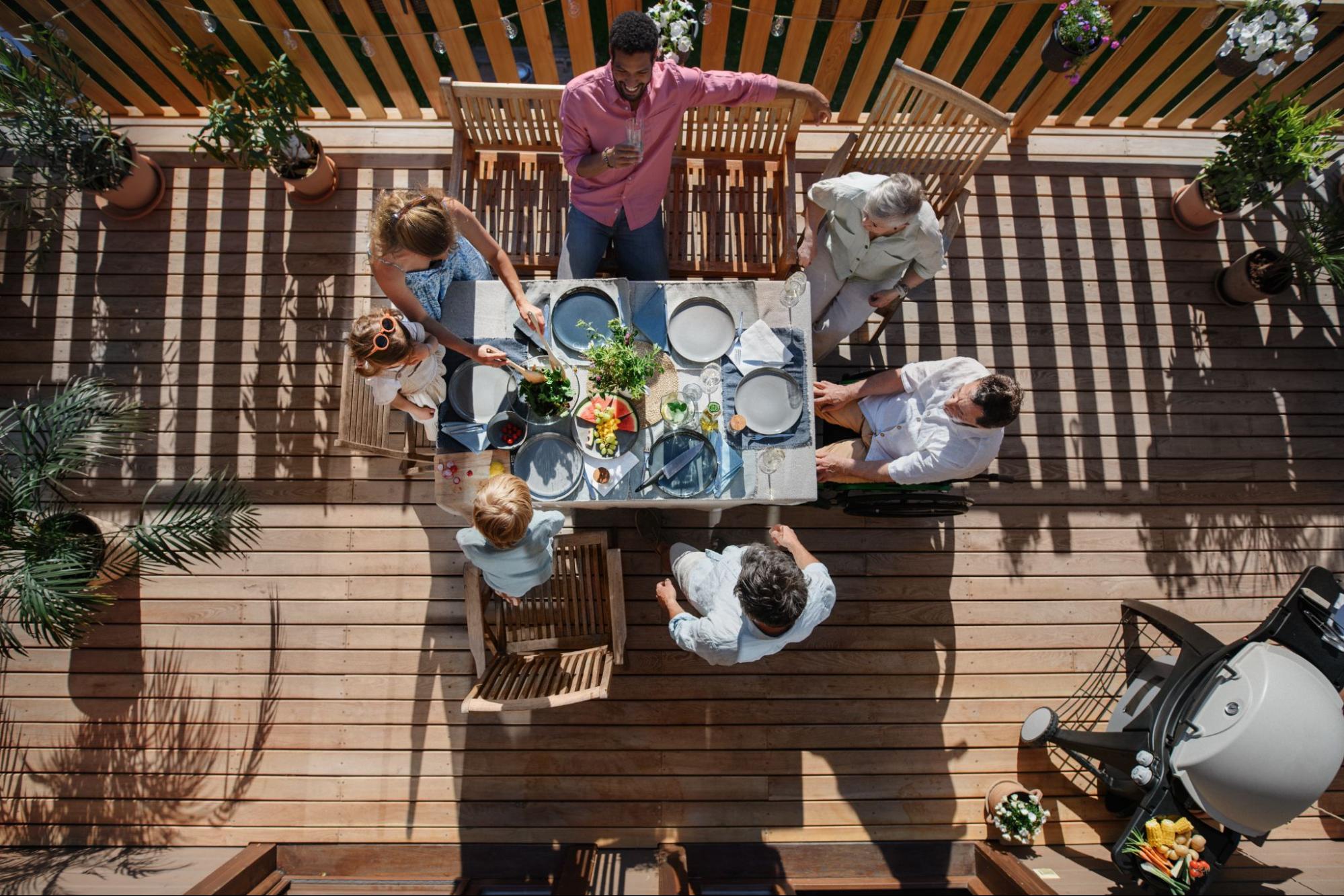Three generations of the family are enjoying a barbeque party on the patio.