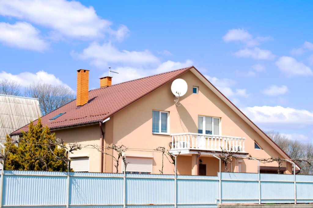 A suburban home in monochromatic brown tones with a contrasting white fence, in a serene residential area.
