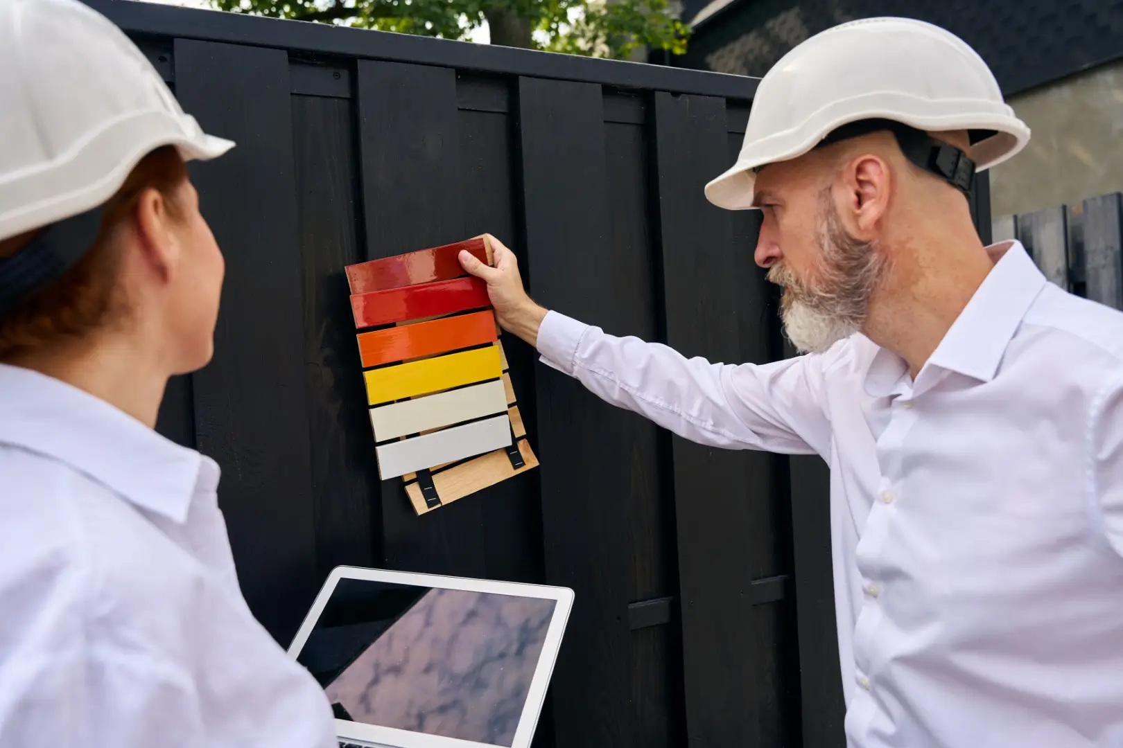 Focused client choosing exterior paint color assisted by specialist.