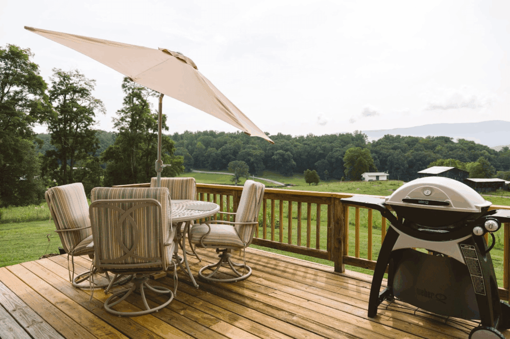 Backyard deck with safety rails, grill, and picnic table setup.