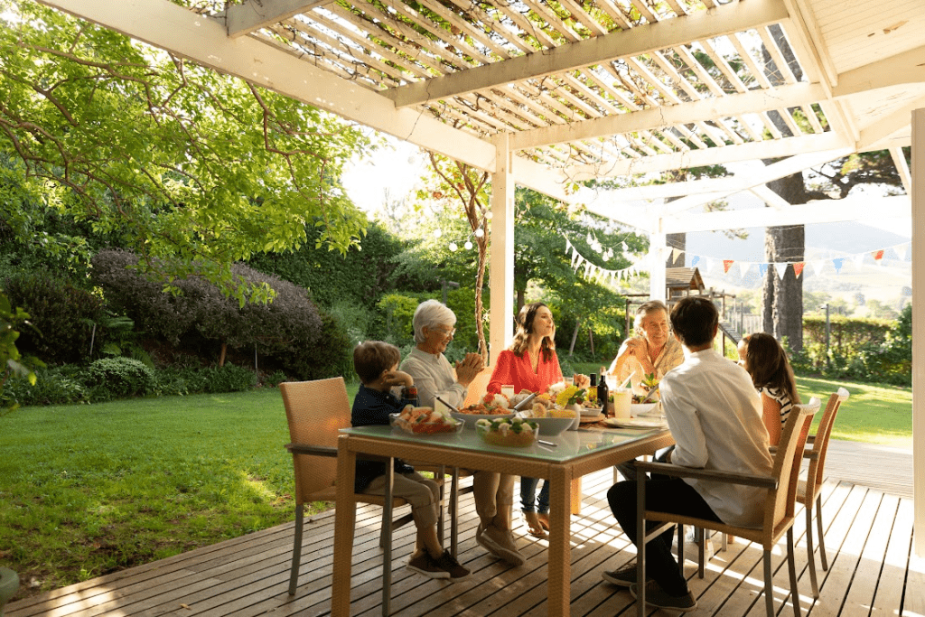 A family is eating outside on a covered patio.