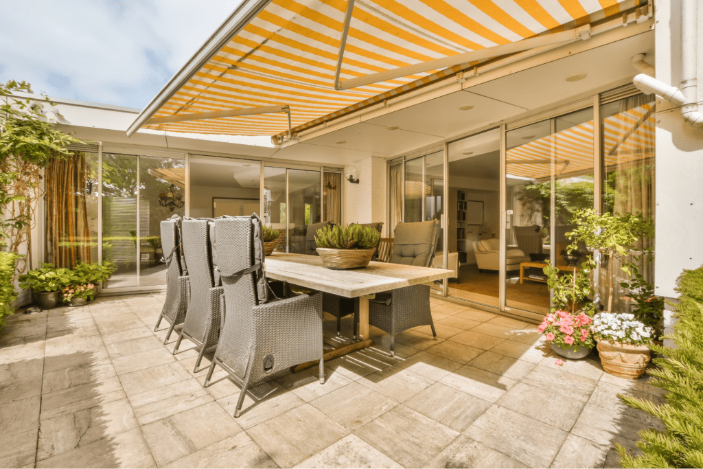 A modern patio covered with an orange striped awning.