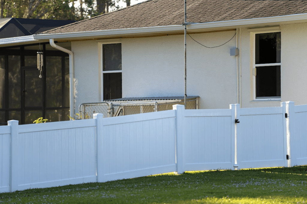 White vinyl picket fence surrounding a backyard.